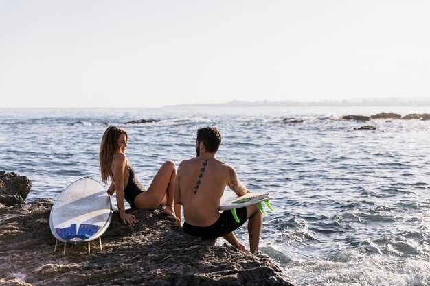 Pareja con tablas de surf mirándose en la orilla del mar