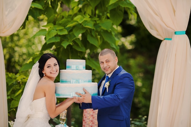 Foto gratuita pareja con la tarta de bodas en sus manos