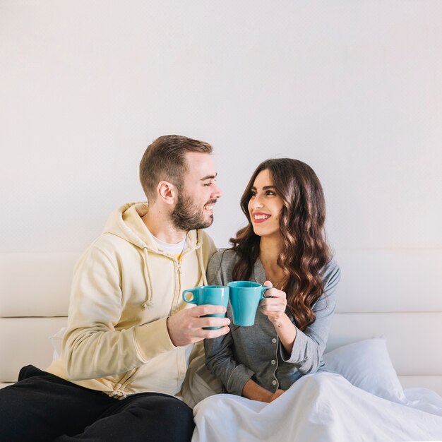 Pareja con tazas en la cama