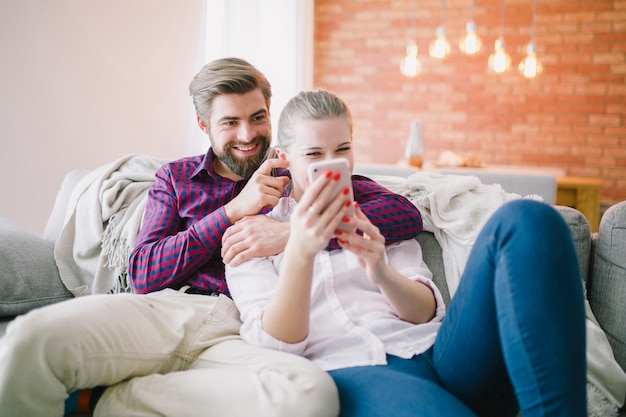 Foto gratuita pareja con teléfono inteligente en casa