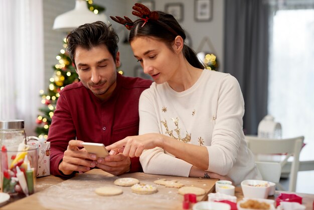 Pareja con teléfono móvil en la cocina