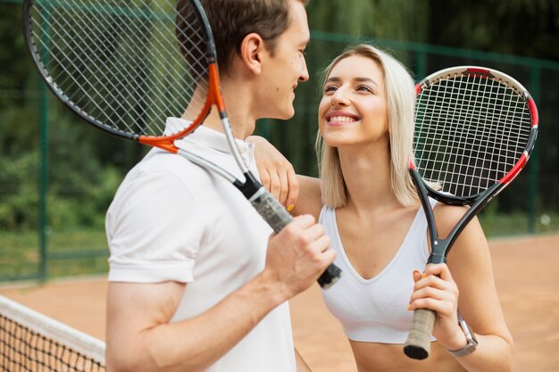 Pareja de tenis sonriendo el uno al otro