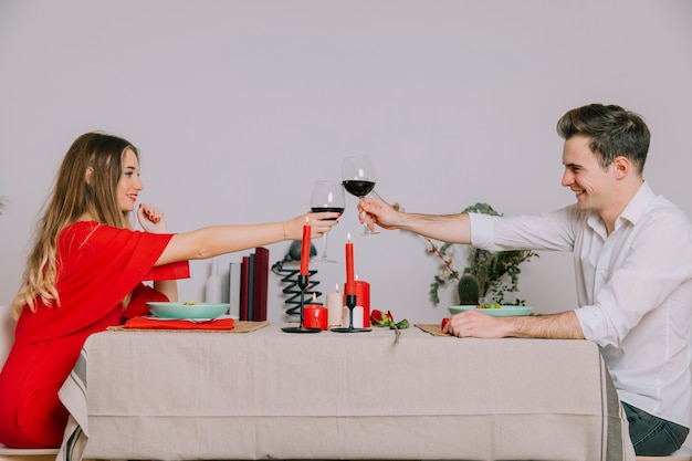 Foto gratuita pareja tintineo de vasos en una cena romántica