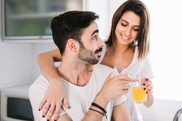 Pareja tintineo vasos con jugo de naranja