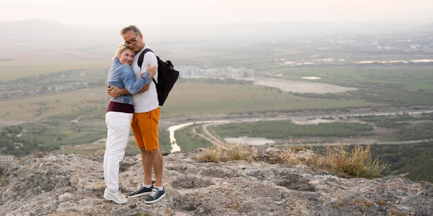 Pareja de tiro completo abrazándose en acantilado