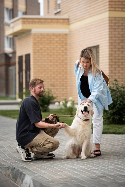 Pareja de tiro completo acariciar a un perro al aire libre