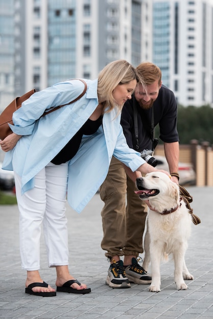 Pareja de tiro completo acariciar a un perro