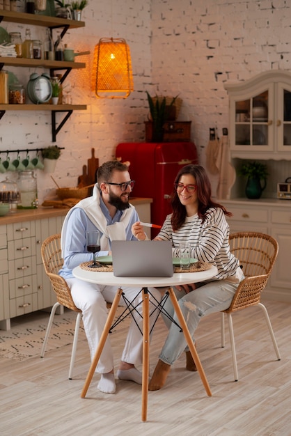 Foto gratuita pareja de tiro completo anunciando embarazo con computadora portátil