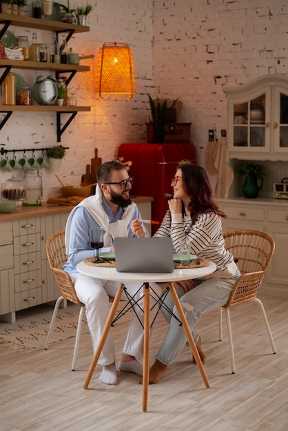 Foto gratuita pareja de tiro completo anunciando embarazo con computadora portátil