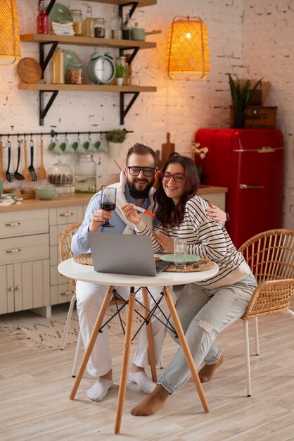 Pareja de tiro completo anunciando embarazo con computadora portátil