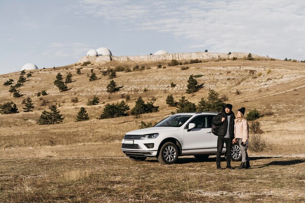 Pareja de tiro completo cerca del coche