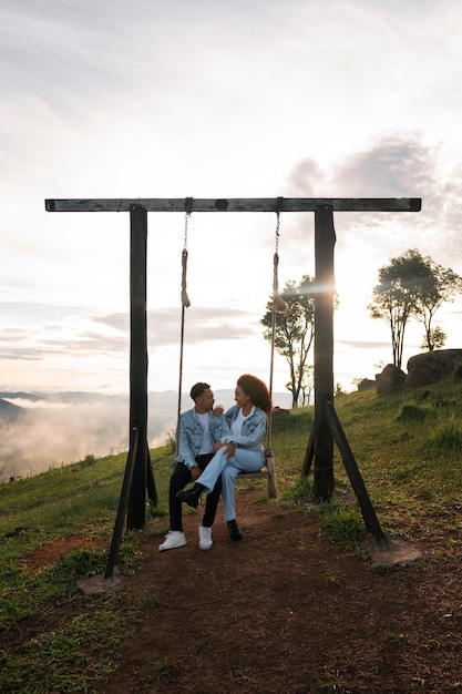 Foto gratuita pareja de tiro completo en columpio al aire libre