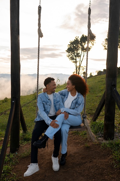 Foto gratuita pareja de tiro completo en columpio al aire libre