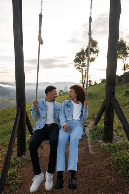 Foto gratuita pareja de tiro completo en columpio al aire libre