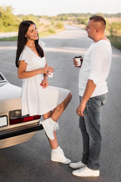 Pareja de tiro completo hablando cerca del coche