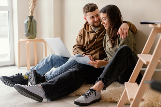 Foto gratuita pareja de tiro completo con portátil en el interior