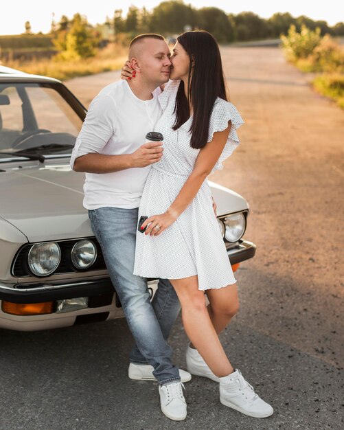 Pareja de tiro completo posando cerca del coche