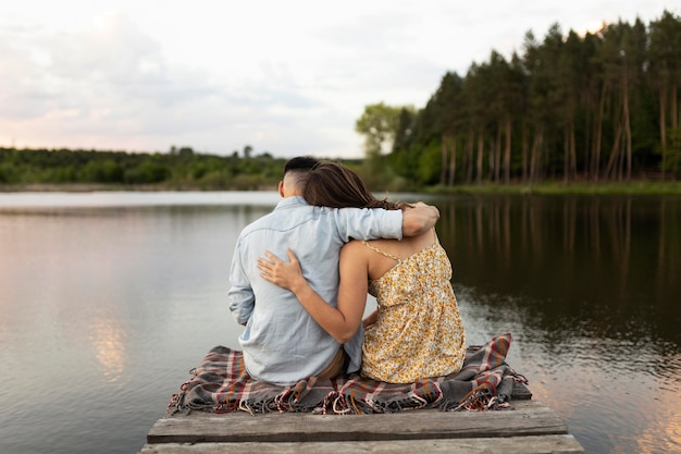 Pareja de tiro completo sentado junto al lago