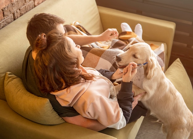 Foto gratuita pareja de tiro completo en el sofá con el perro