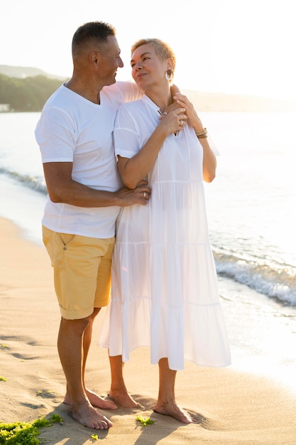 Pareja de tiro completo sosteniendo en la playa