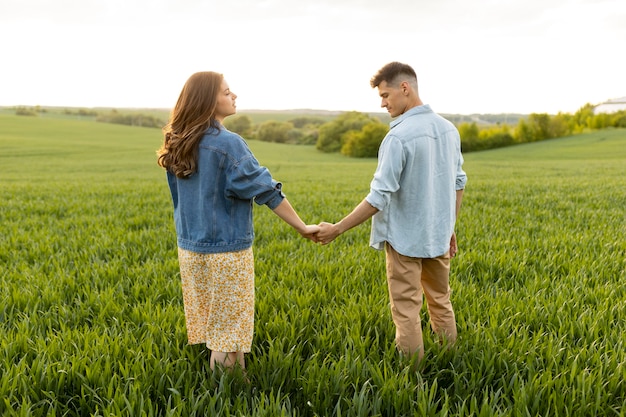 Pareja de tiro completo tomados de la mano al aire libre