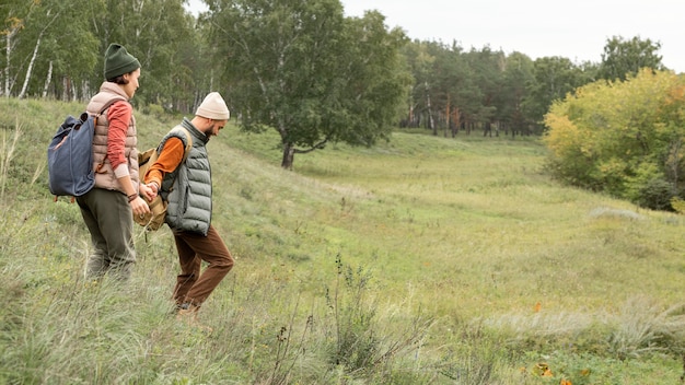 Pareja de tiro completo tomados de la mano y caminar en la naturaleza