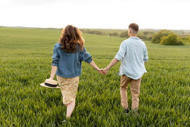 Pareja de tiro completo tomados de la mano en la naturaleza