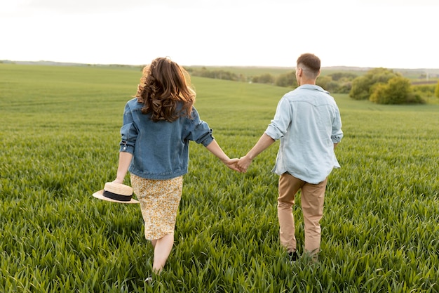 Pareja de tiro completo tomados de la mano en la naturaleza