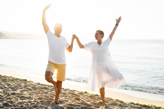 Pareja de tiro completo tomados de la mano en la playa