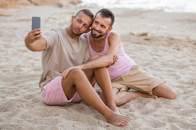 Pareja de tiro completo tomando selfies en la playa