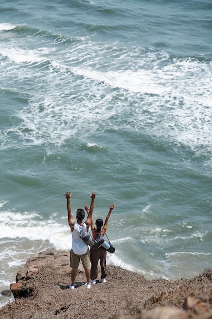 Pareja de tiro largo con las manos en alto en la playa