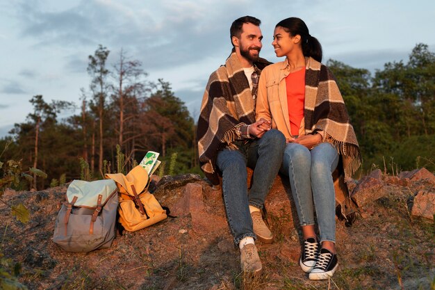 Pareja de tiro largo sentado en las rocas y mirando el uno al otro