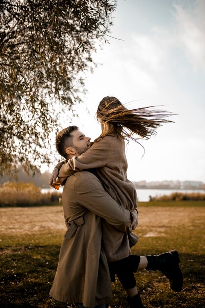 Pareja de tiro medio abrazándose al aire libre