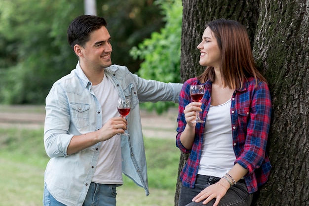 Pareja de tiro medio bebiendo vino tinto en el parque