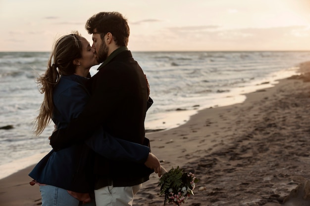 Pareja de tiro medio besándose en la playa