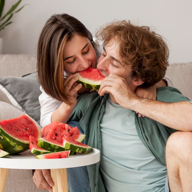 Pareja de tiro medio comiendo sandía