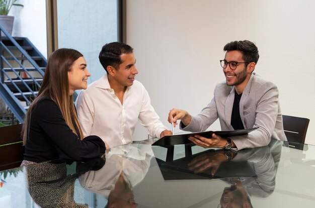 Pareja de tiro medio hablando con agente inmobiliario