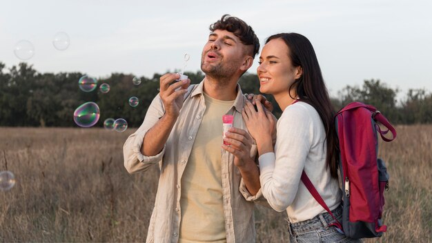 Pareja de tiro medio haciendo globos de jabón