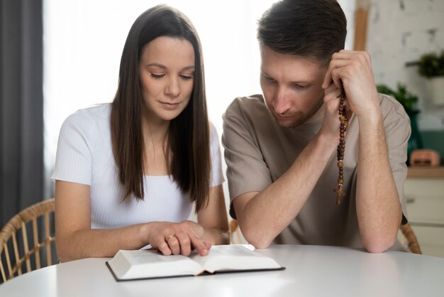 Pareja de tiro medio leyendo la biblia juntos