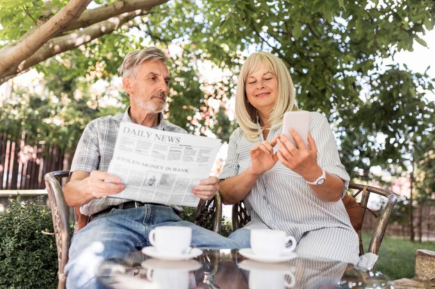 Pareja de tiro medio leyendo noticias