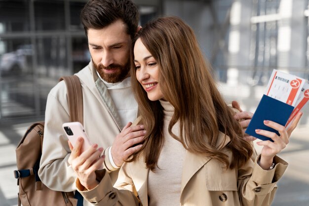 Pareja de tiro medio mirando el teléfono