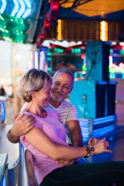 Pareja de tiro medio en el parque de atracciones sentado