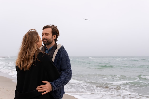 Pareja de tiro medio pasando tiempo en la playa