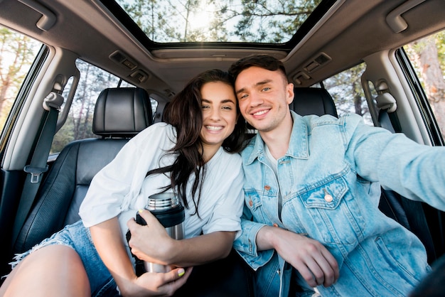 Pareja de tiro medio posando en coche