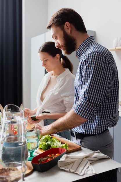 Pareja de tiro medio preparando comida en casa