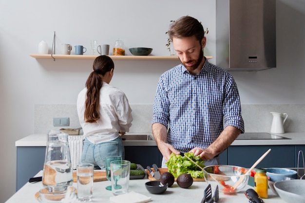 Pareja de tiro medio preparando comida sabrosa