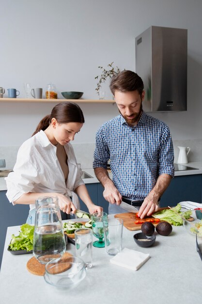 Pareja de tiro medio preparando comida sana