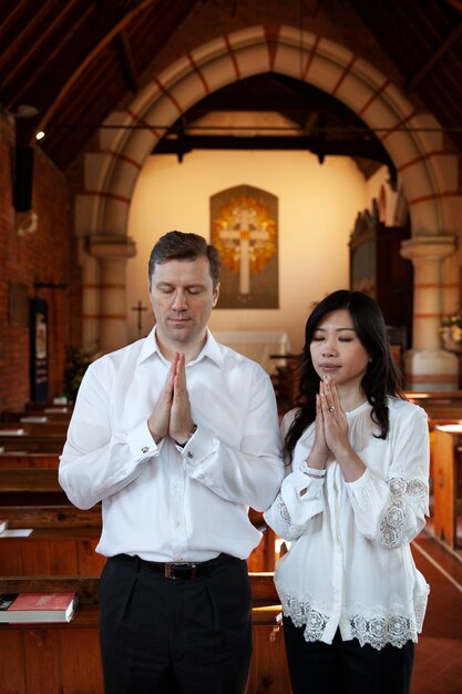 Pareja de tiro medio rezando en la iglesia