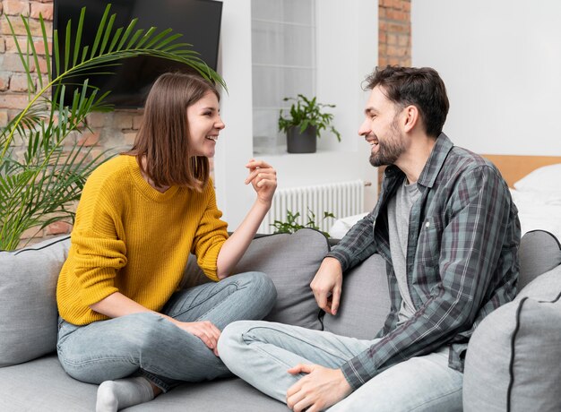 Pareja de tiro medio riendo en el sofá