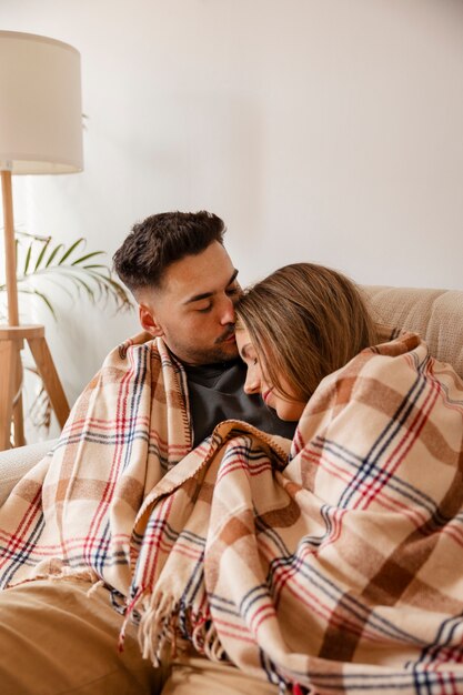 Pareja de tiro medio siendo cariñosa en el interior